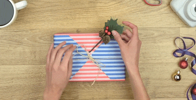 Manos de mujer esccribiendo un mensaje en foto y poniéndola sobre el regalo envuelto.
